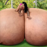 Ricki Raxxx laying over her giant tits in the park
